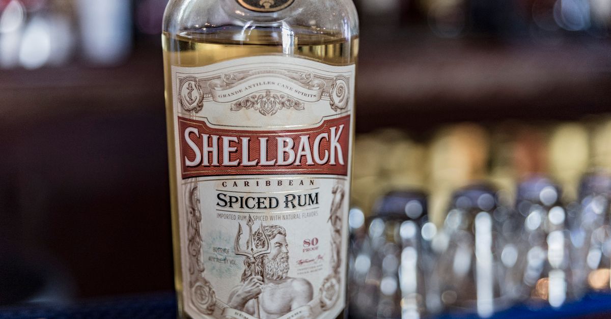 A detailed close-up of Shellback Caribbean Spiced Rum with a blurred bar background.